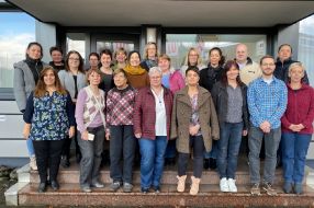 Eine Gruppe von Menschen steht lächelnd auf den Stufen eines Gebäudes.