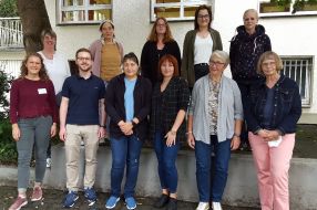 Eine Gruppe von Personen posiert lächelnd für ein Foto, das die erfolgreiche Nachbarschaftshilfe zeigt.