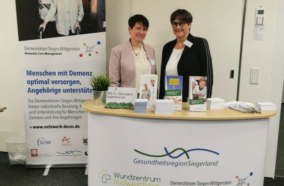 Zwei Frauen stehen an einem Informationsstand zum Thema Demenzversorgung in der Gesundheitsregion Siegenland.