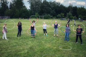 Eine Gruppe von Frauen steht mit Hula-Hoop-Reifen im Freien auf einer grünen Wiese.