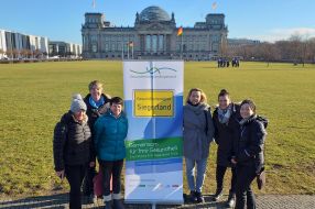 Eine Gruppe von Frauen steht lächelnd vor einem Banner der Gesundheitsregion Siegerland vor dem Reichstagsgebäude.