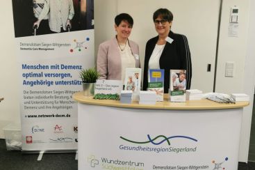 Zwei Frauen stehen an einem Informationsstand zum Thema Demenzversorgung in der Gesundheitsregion Siegenland.