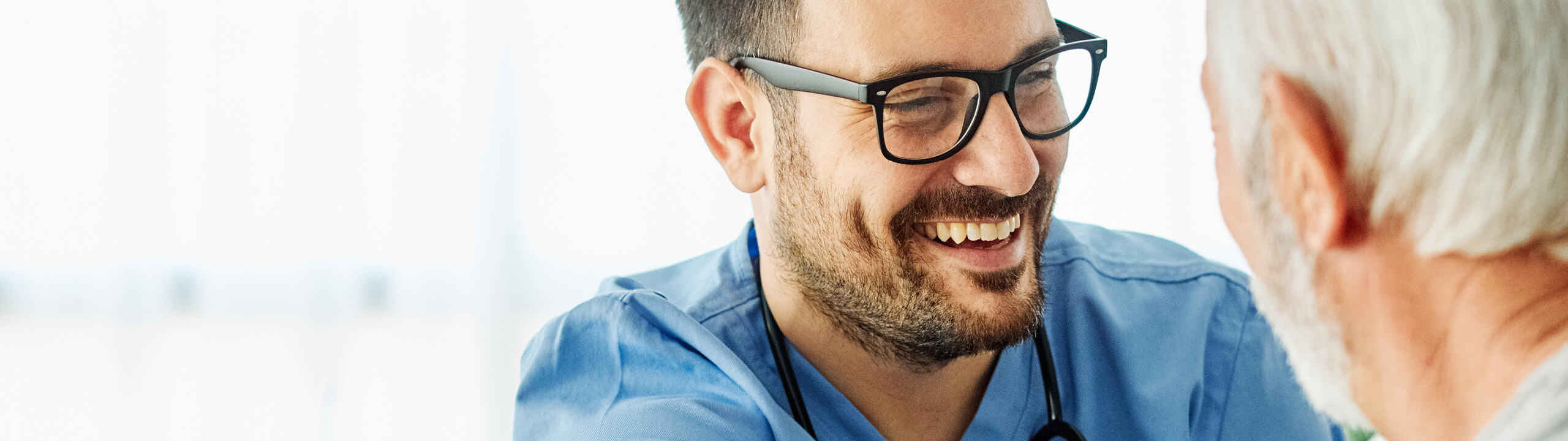 Ein lächelnder Mann im blauen Hemd führt ein freundliches Gespräch mit einem älteren Mann.