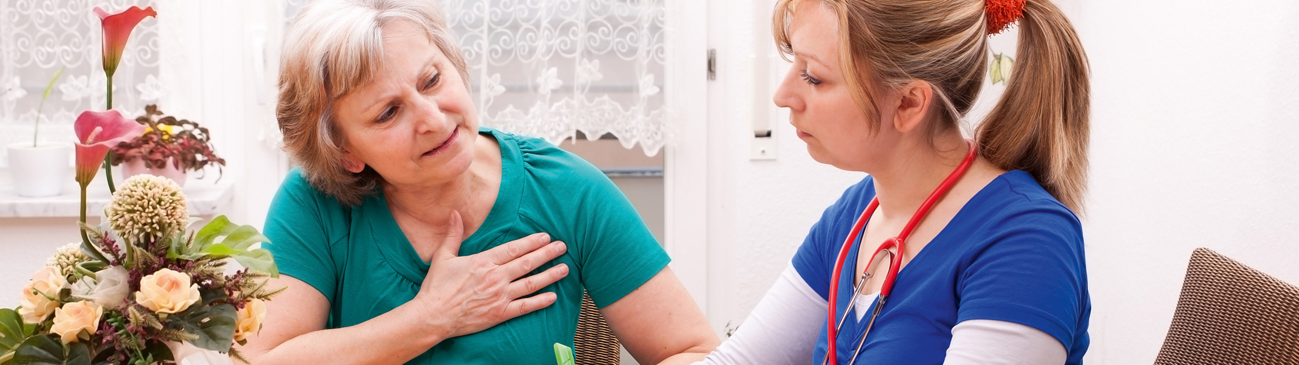 Eine ältere Frau zeigt Anzeichen von Unwohlsein, während eine Ärztin sie betreut.